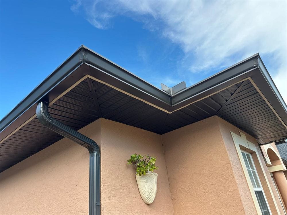 Bronze gutter and downspout meeting the soffit at a building corner.